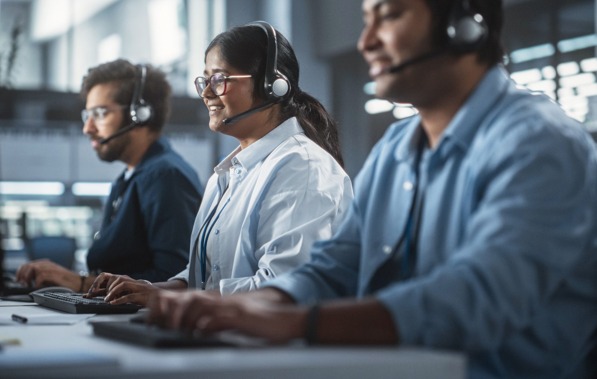 Three agents on headset calls at a shared desk