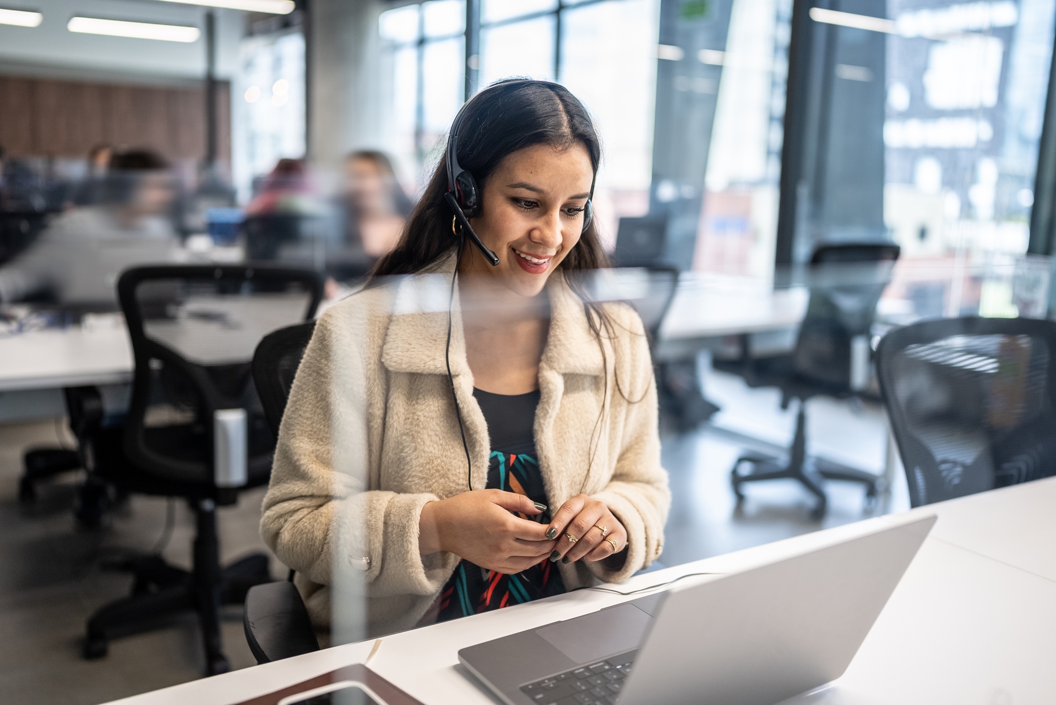 Agent on a headset call at a laptop in an open office