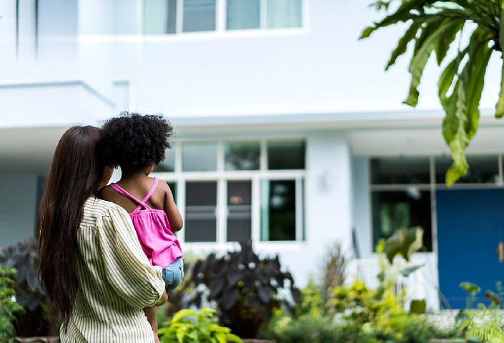Parent holding a child outside a house, from the OnCourse Home Solutions customer story