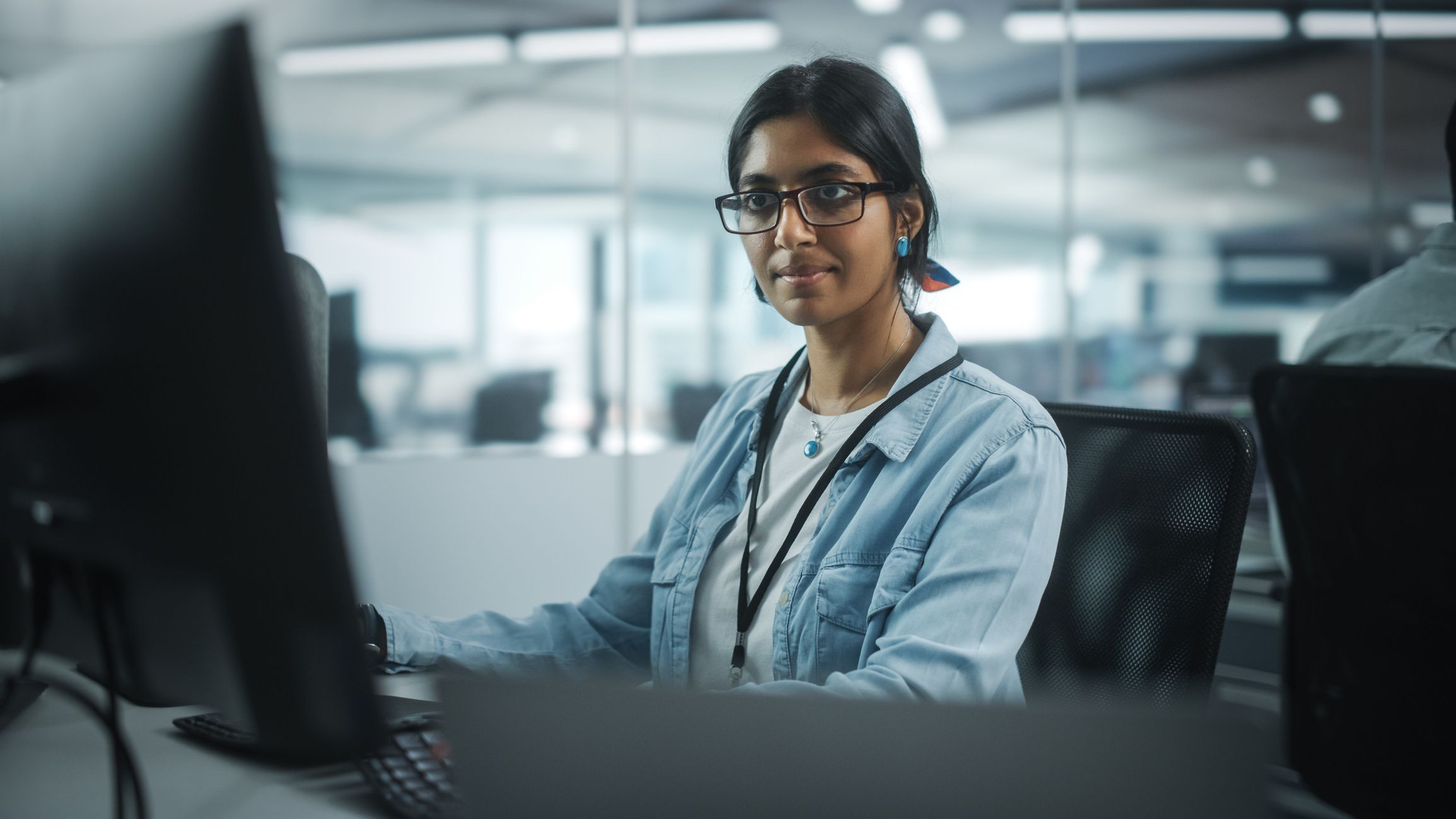 Person in glasses working at a desk in an open office